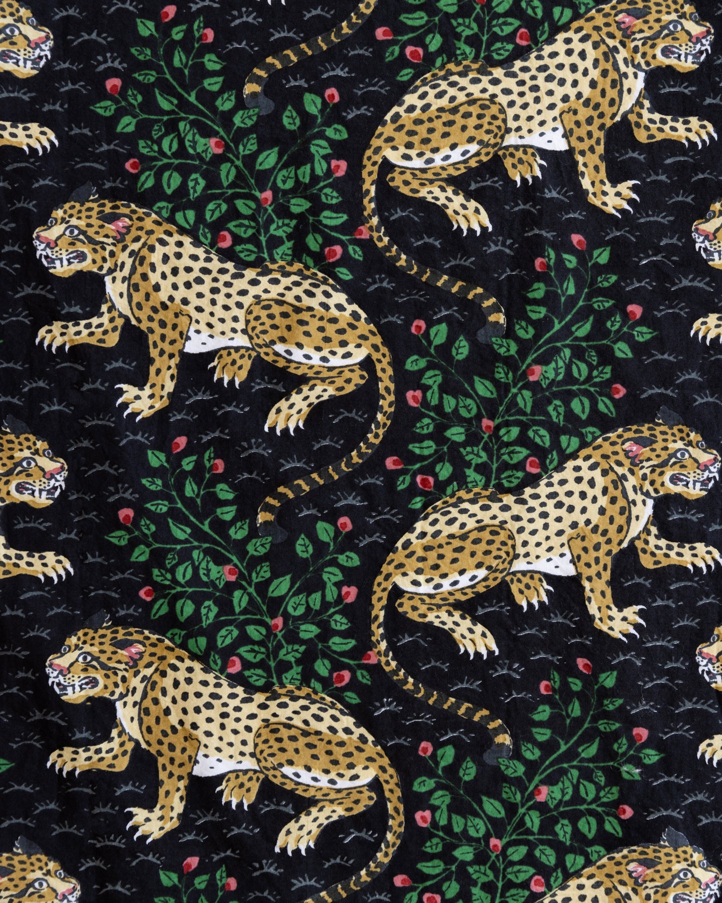 Close-up of the Bagheera print with spotted leopards, leafy branches, and red flowers on a black background