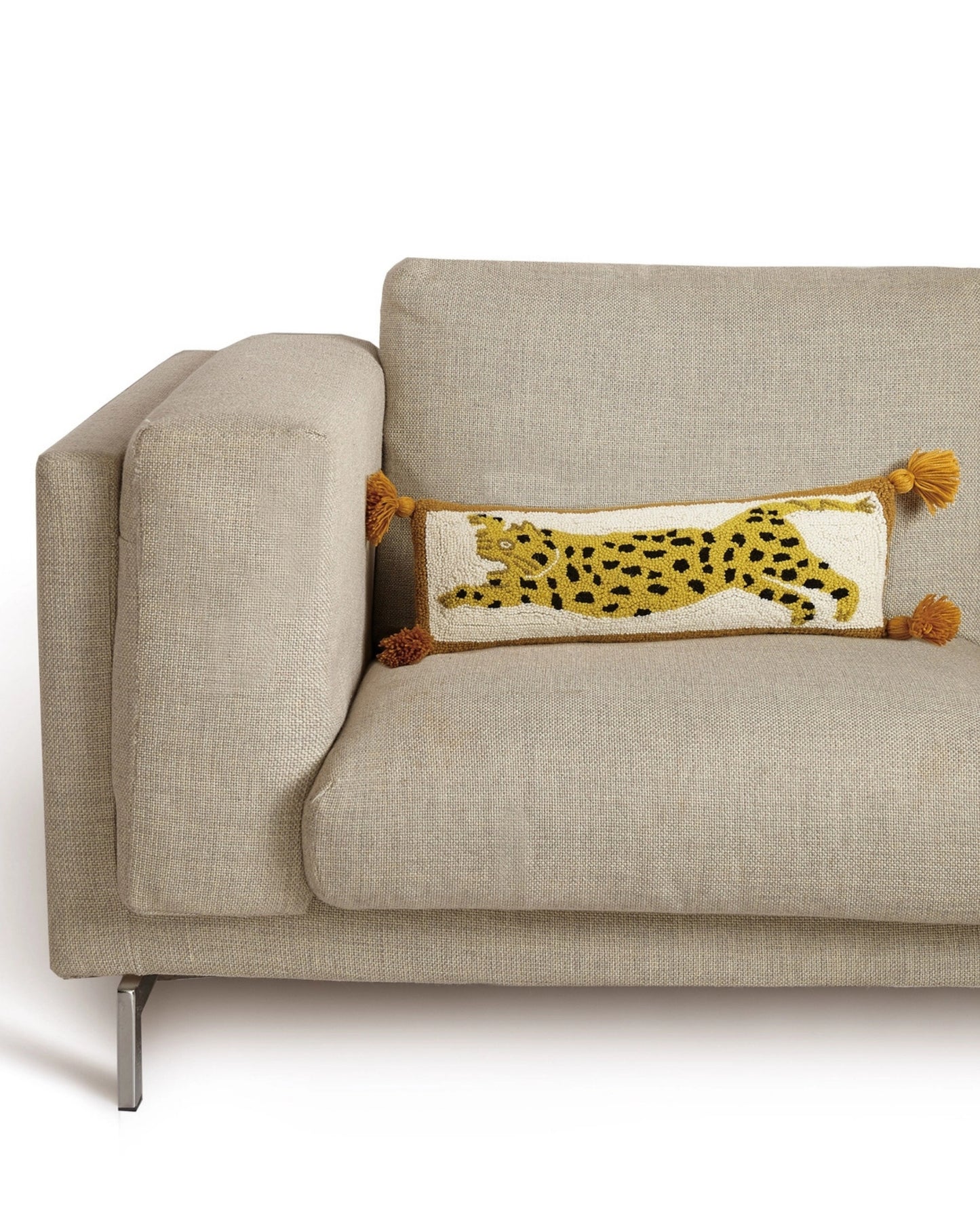 Chi Chi hook pillow with a spotted leopard design displayed on a beige sofa.