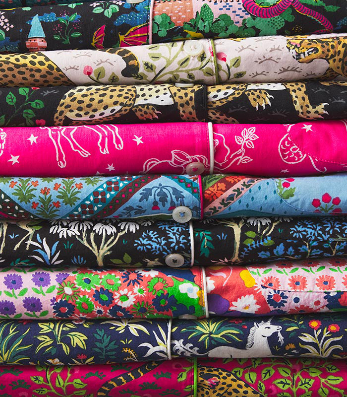 Stack of folded colorful patterned textiles featuring animals, plants, flowers, and abstract designs