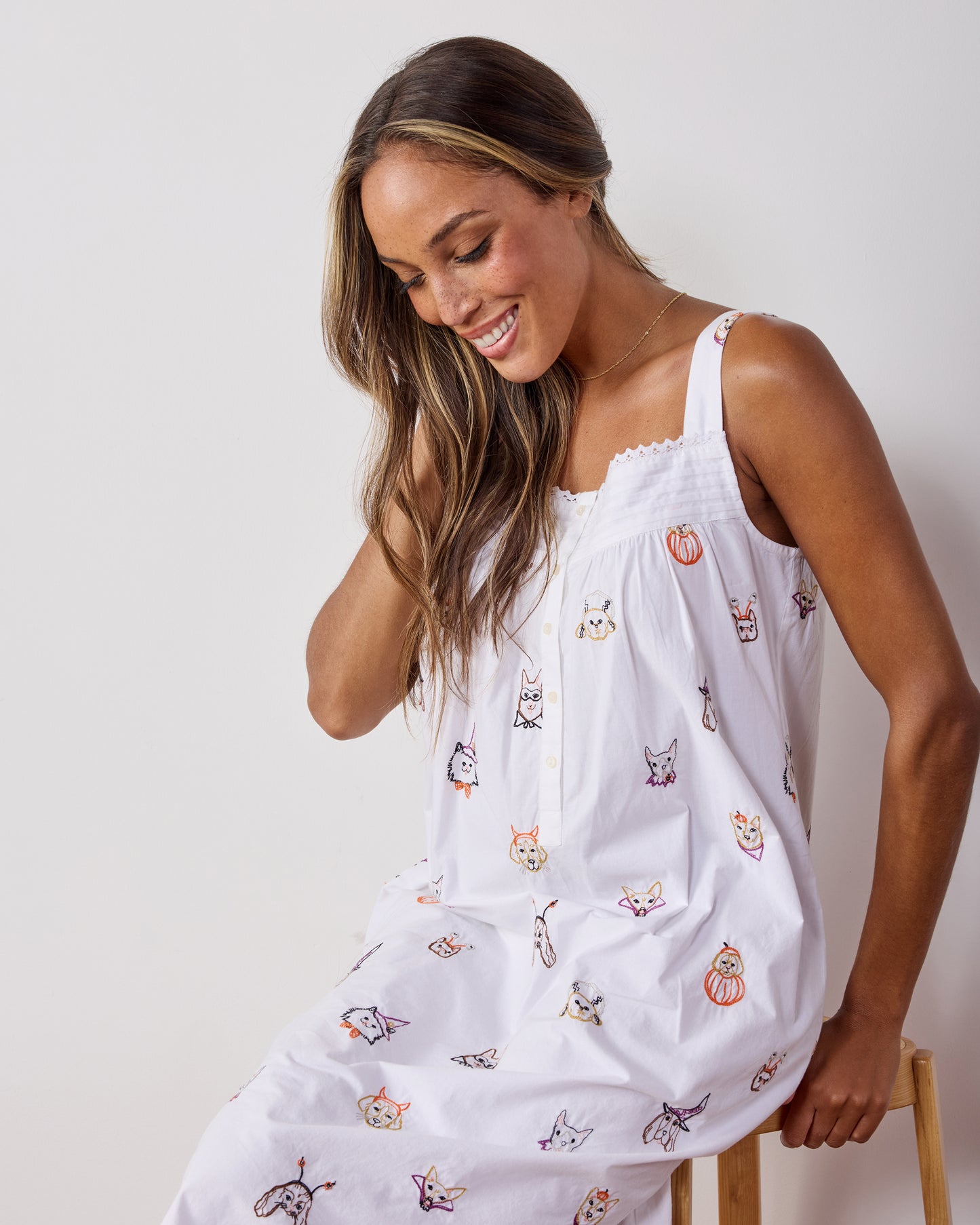 Model wearing the Halloween Hounds embroidered dog-print back-to-bed nightgown, shown seated in a three-quarter view.