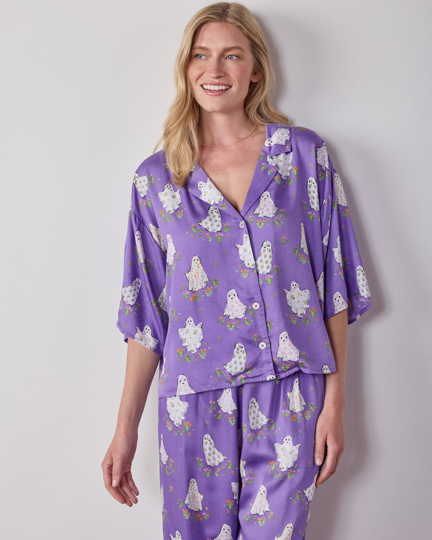 Front view of the purple Gardening Ghosts pajama set with a collared button-front top and wide-leg pants covered in a white ghost-and-floral print.