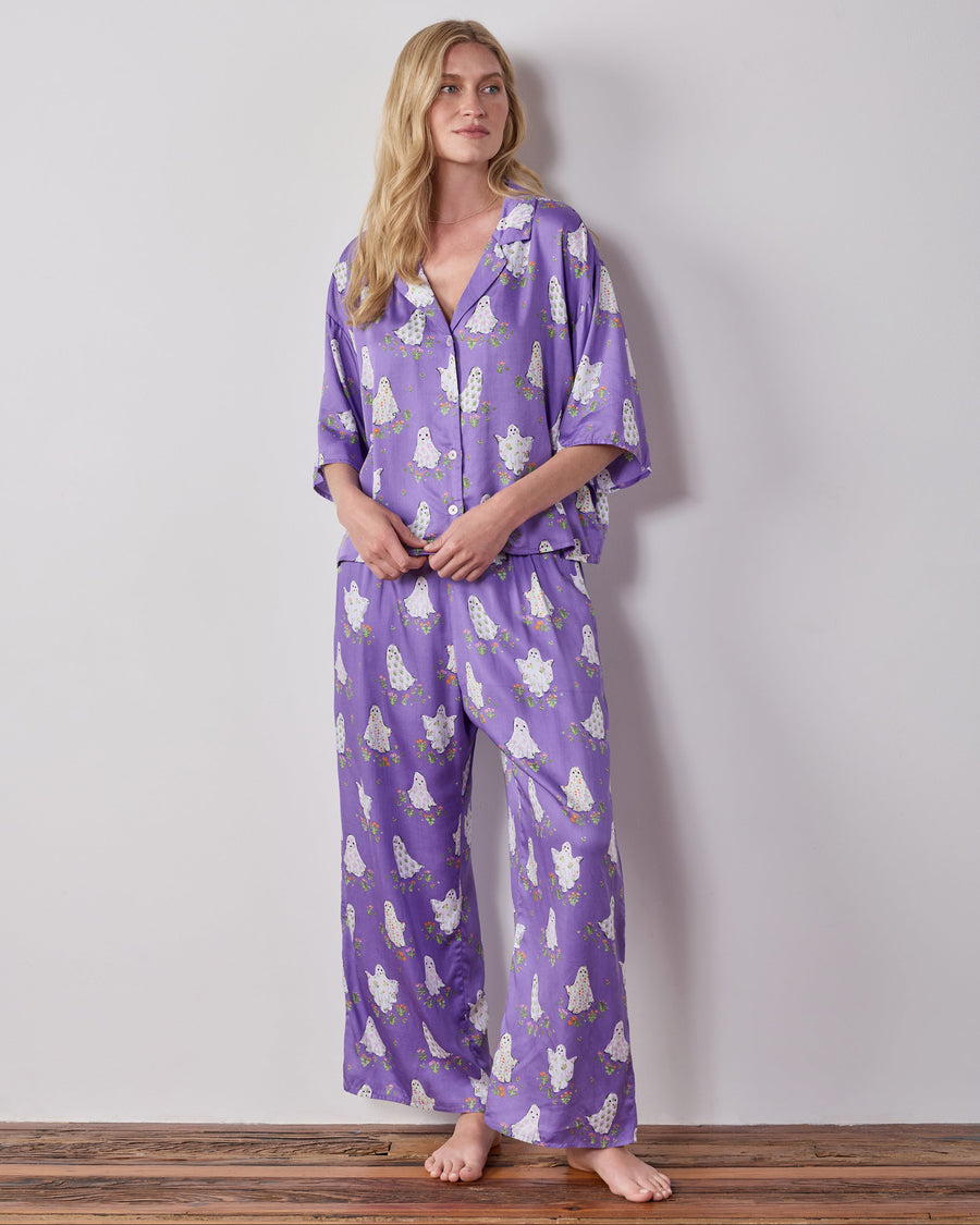 Model wearing the Gardening Ghosts petite pajama set with a purple ghost-and-floral print, cropped top, and wide-leg pants.