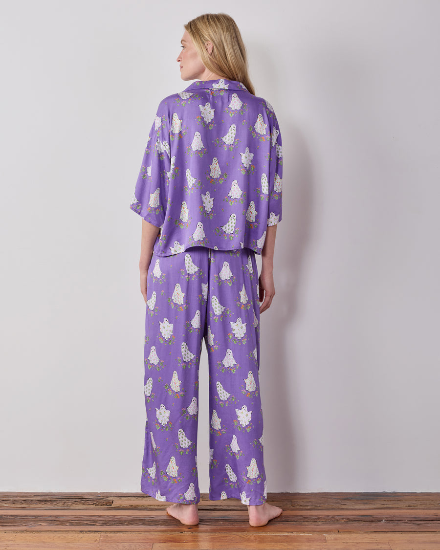 Back view of the purple Gardening Ghosts pajama set showing the collared top and wide-leg pants with a white ghost-and-floral print.