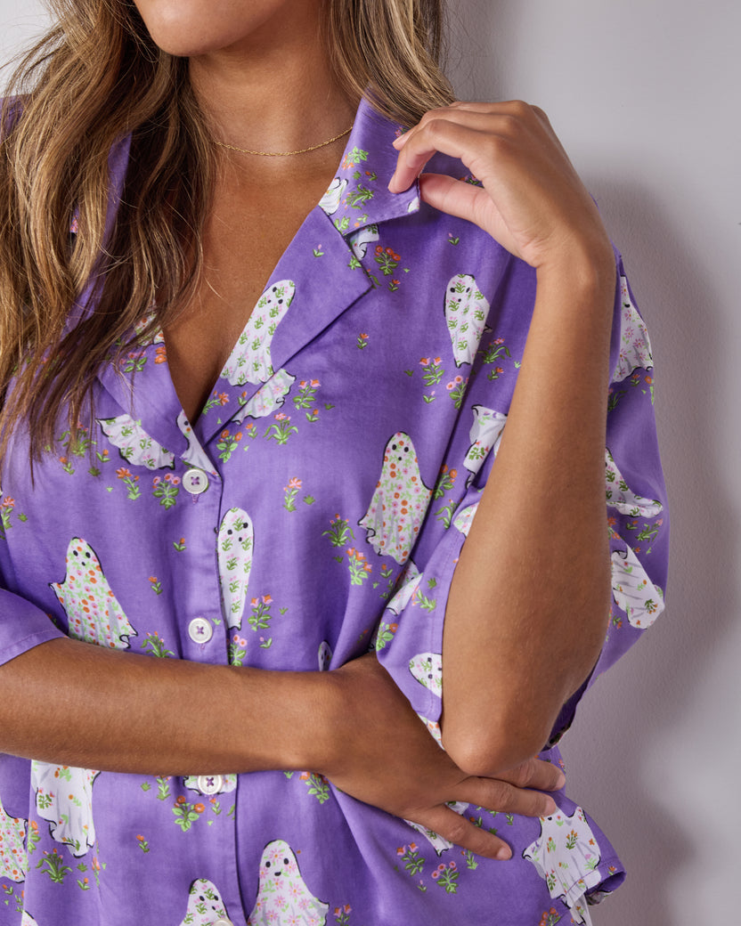 Close-up of the Eerie Amethyst pajama top showing the collar, front buttons, sleeve, and ghost-and-flower print.