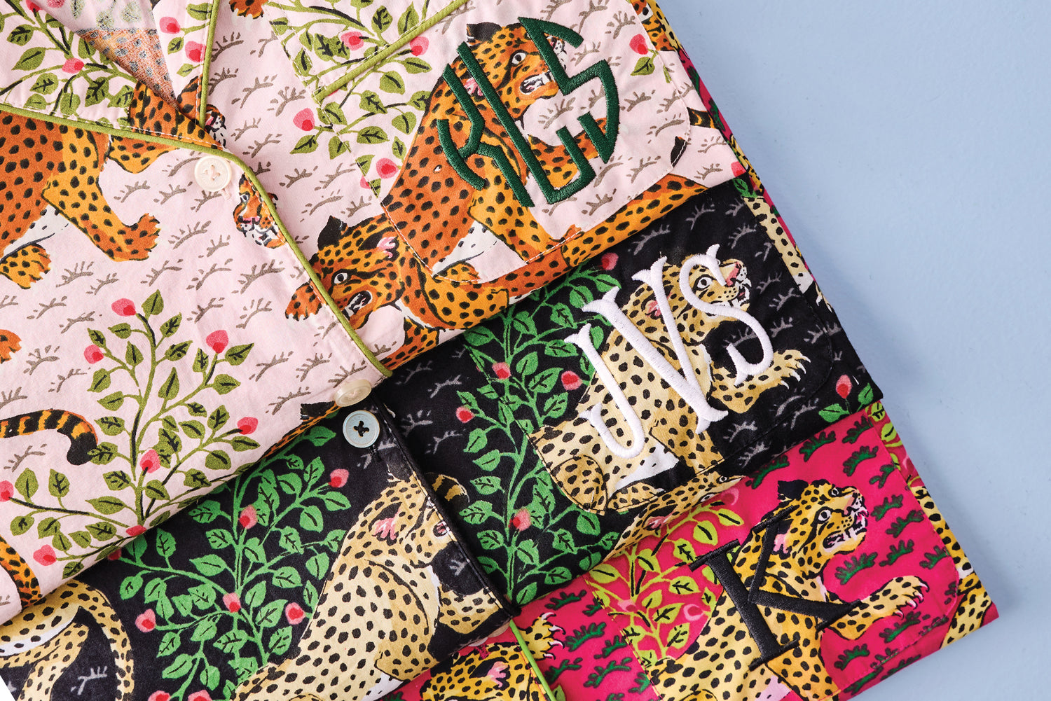 Patterned monogrammed pajama clothing featuring spotted cats, foliage, and colorful fabric panels. 