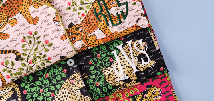 Patterned pajamas with orange spotted cats, foliage, and white monogram lettering. 
