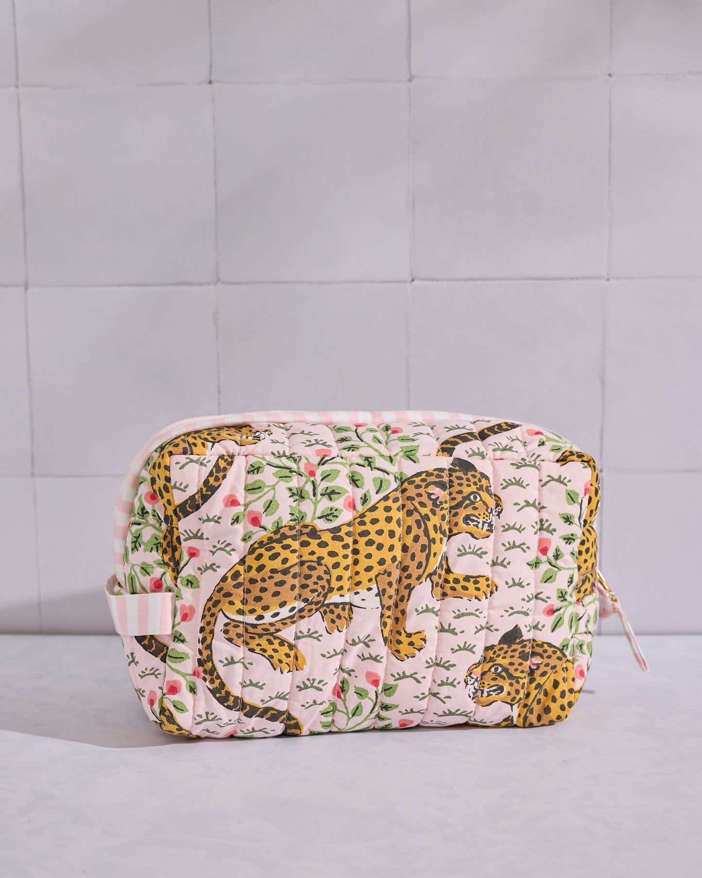 Front view of a pale pink quilted Bagheera pouch with leopard and leafy motifs.