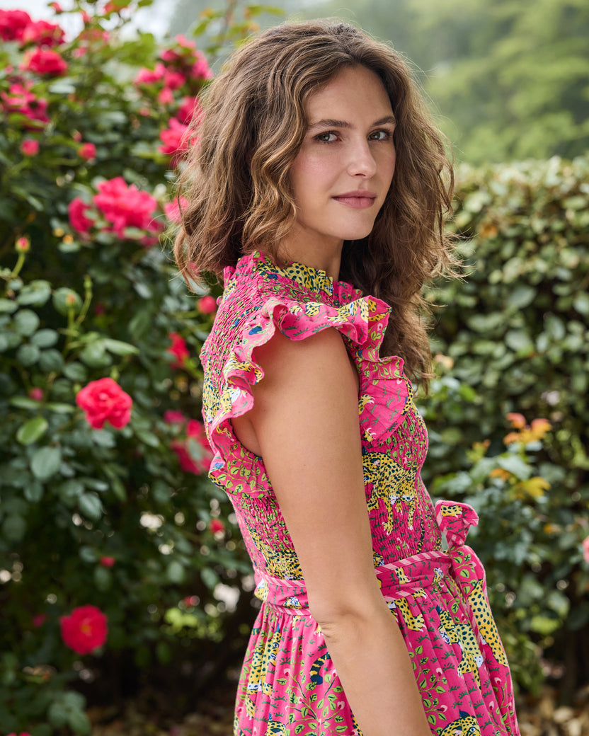 Model shown from the side wearing the hot pink Bagheera Let's Ruffle Dress with a leopard print, flutter sleeves, ruffled neckline, smocked bodice, tiered skirt, and coordinating belt.