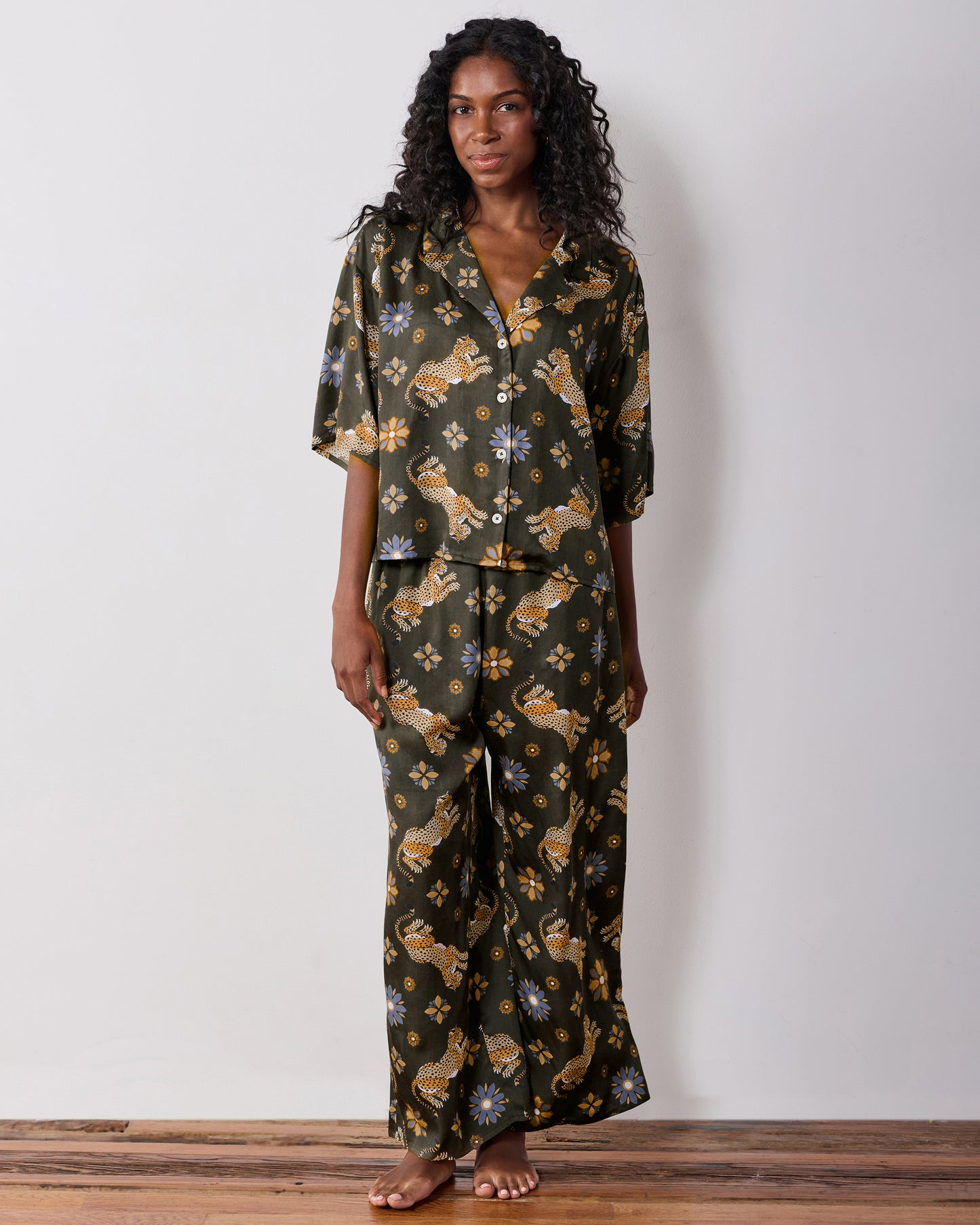 Full-length front view of the olive Wildest Dreams pajama set with a short-sleeve button-front shirt and wide-leg pants featuring leopard and flower prints.