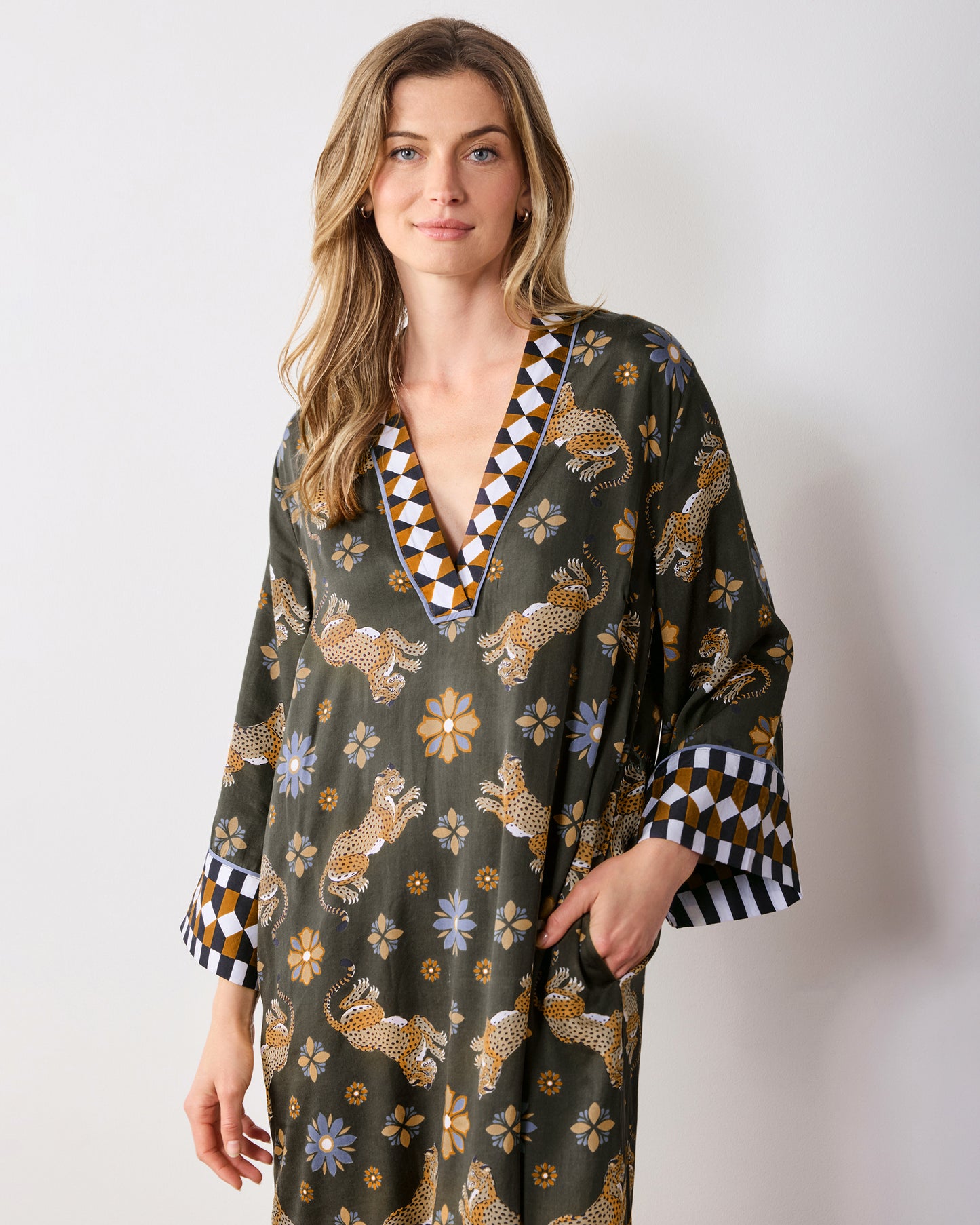 Front three-quarter view of the olive Bagheera Kaleidoscope Kennedy caftan with a V-neck, wide cuffs, leopard-and-flower print, and side pockets.