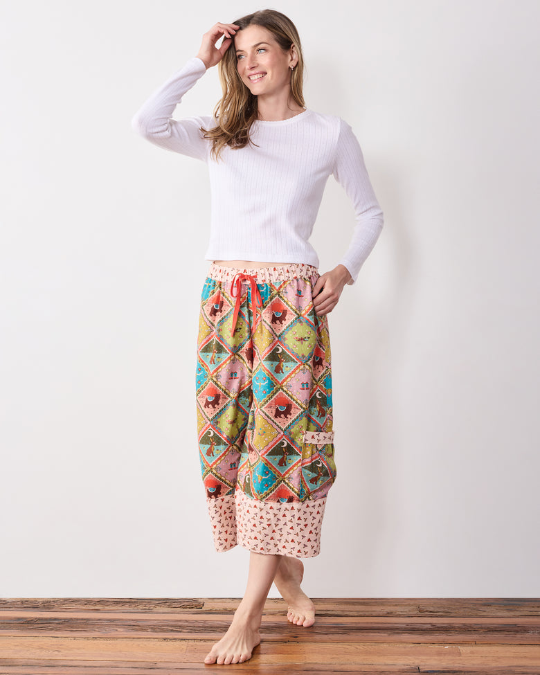 Full view of a model wearing the patterned cropped pants with a white long-sleeve top, drawstring waist, and side pocket.