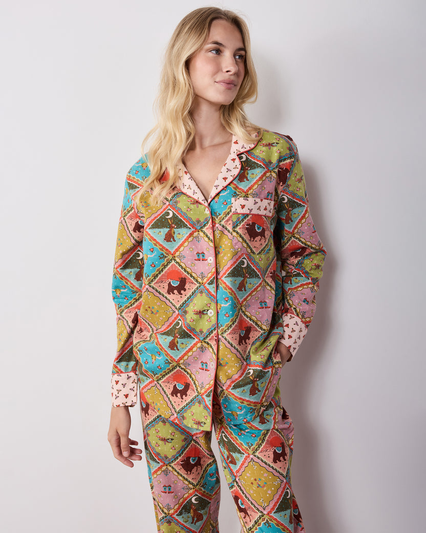 Three-quarter front view of the Western Scenes long pajama set, showing the button-front shirt, chest pocket, side pockets, and matching printed pants.