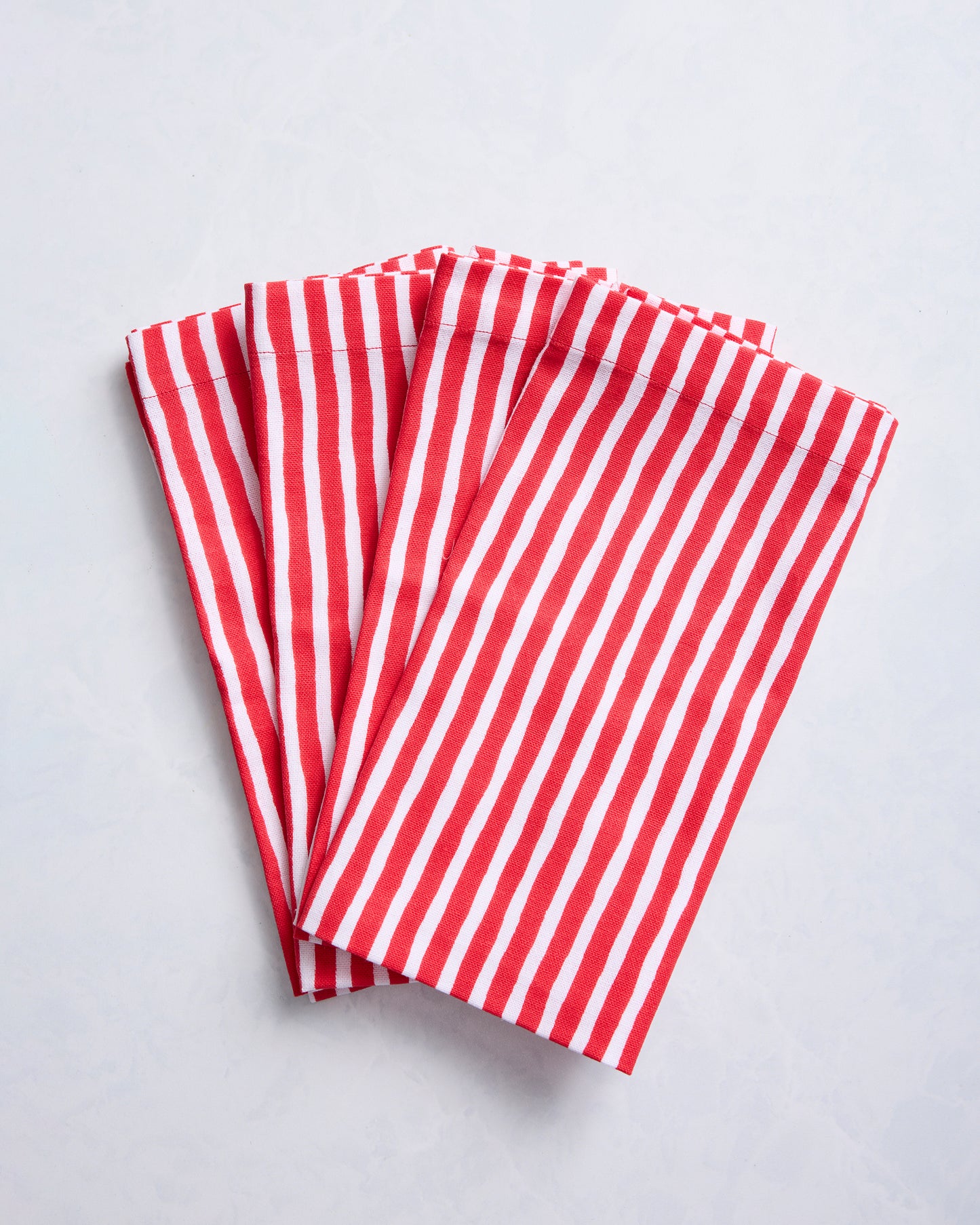 Four folded dinner napkins with red and white painted stripes