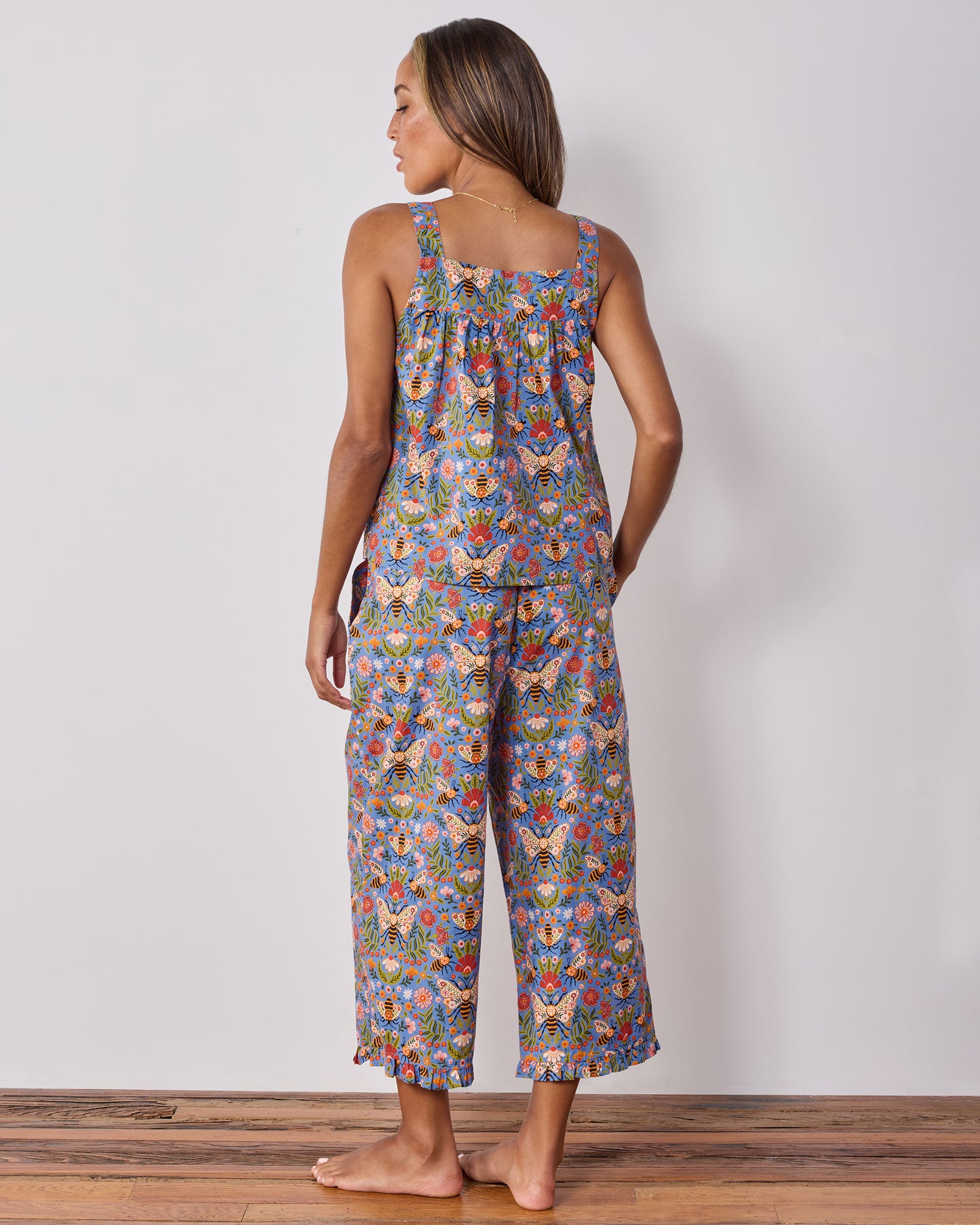Back view of a sleeveless pajama top and wide-leg cropped pants with a blue bee-and-floral print.