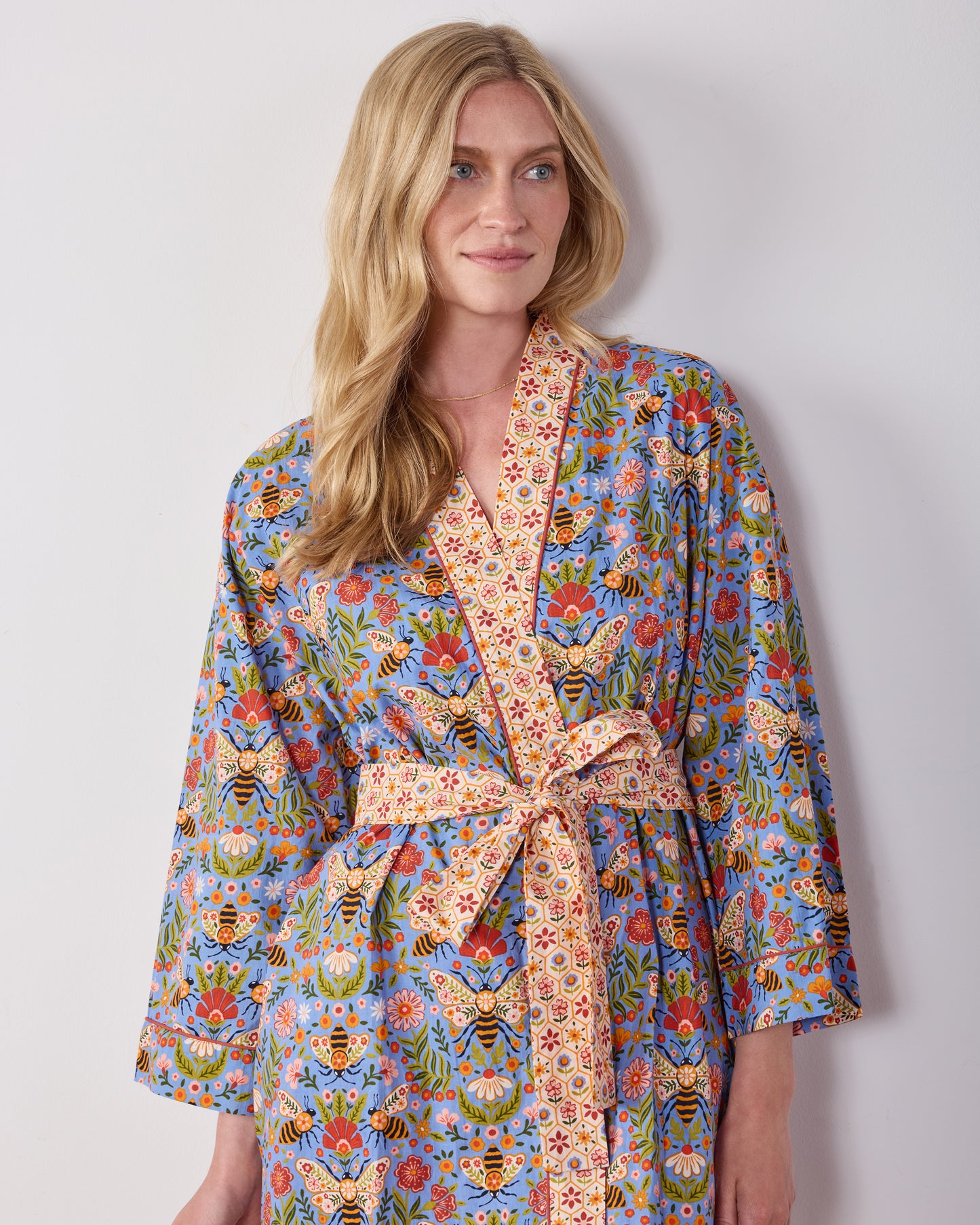 Front view of a person wearing the Delphinium Blue Bee Tapestry robe, highlighting the shawl collar, matching belt, and floral bee print.