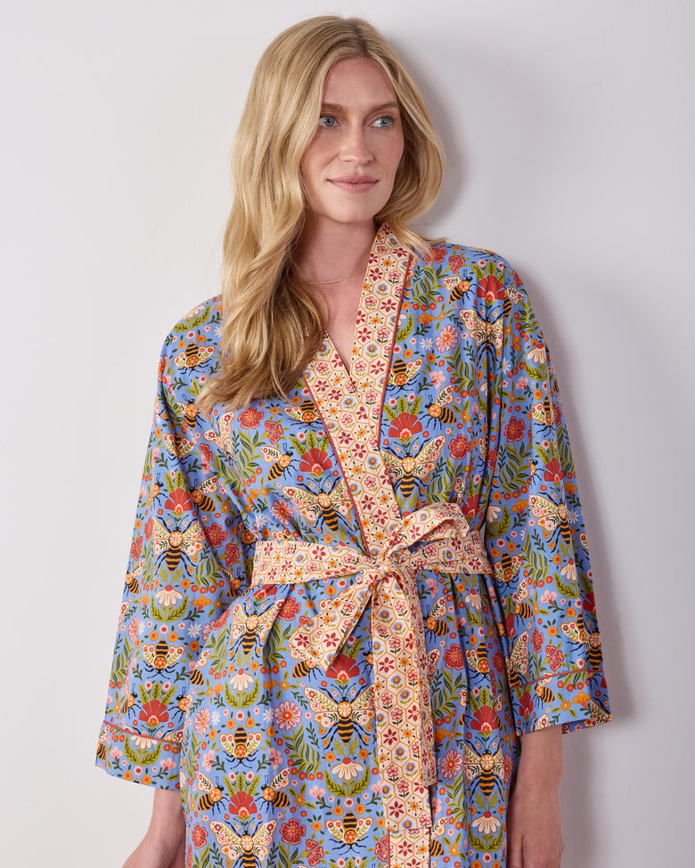 Front view of a person wearing the Delphinium Blue Bee Tapestry robe, highlighting the shawl collar, matching belt, and floral bee print.