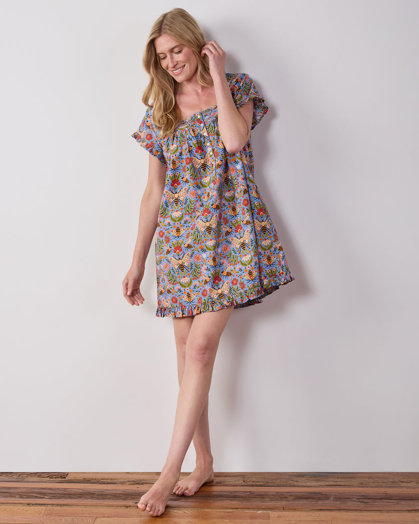 Model wearing the blue Bee Tapestry pintuck nightgown, shown at an angled view with its ruffled hem and short sleeves.