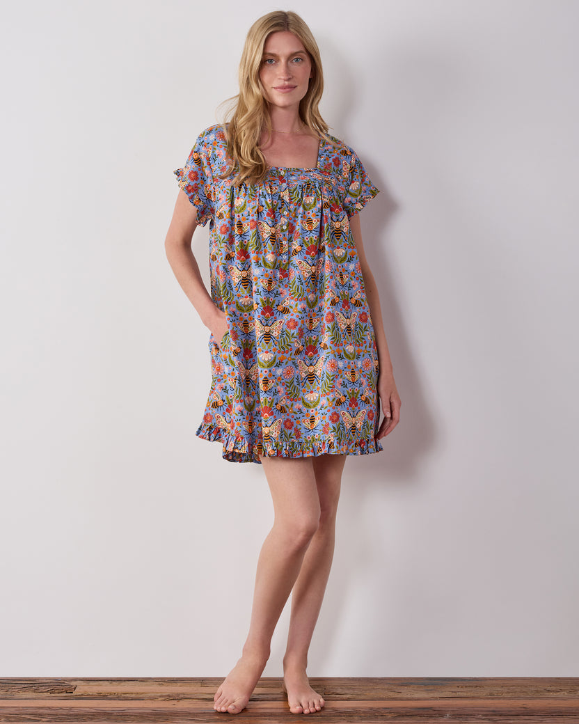 Model wearing the blue Bee Tapestry pintuck nightgown, shown from the front with short sleeves and a ruffled hem.