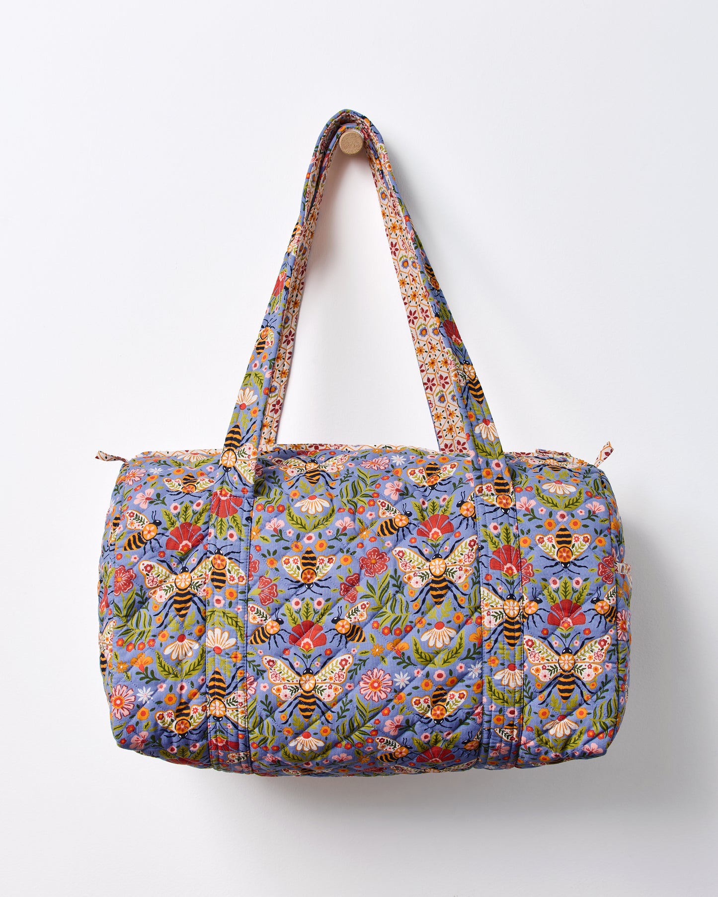 Blue Bee Tapestry quilted duffle bag shown front-facing with two handles and a top zipper.