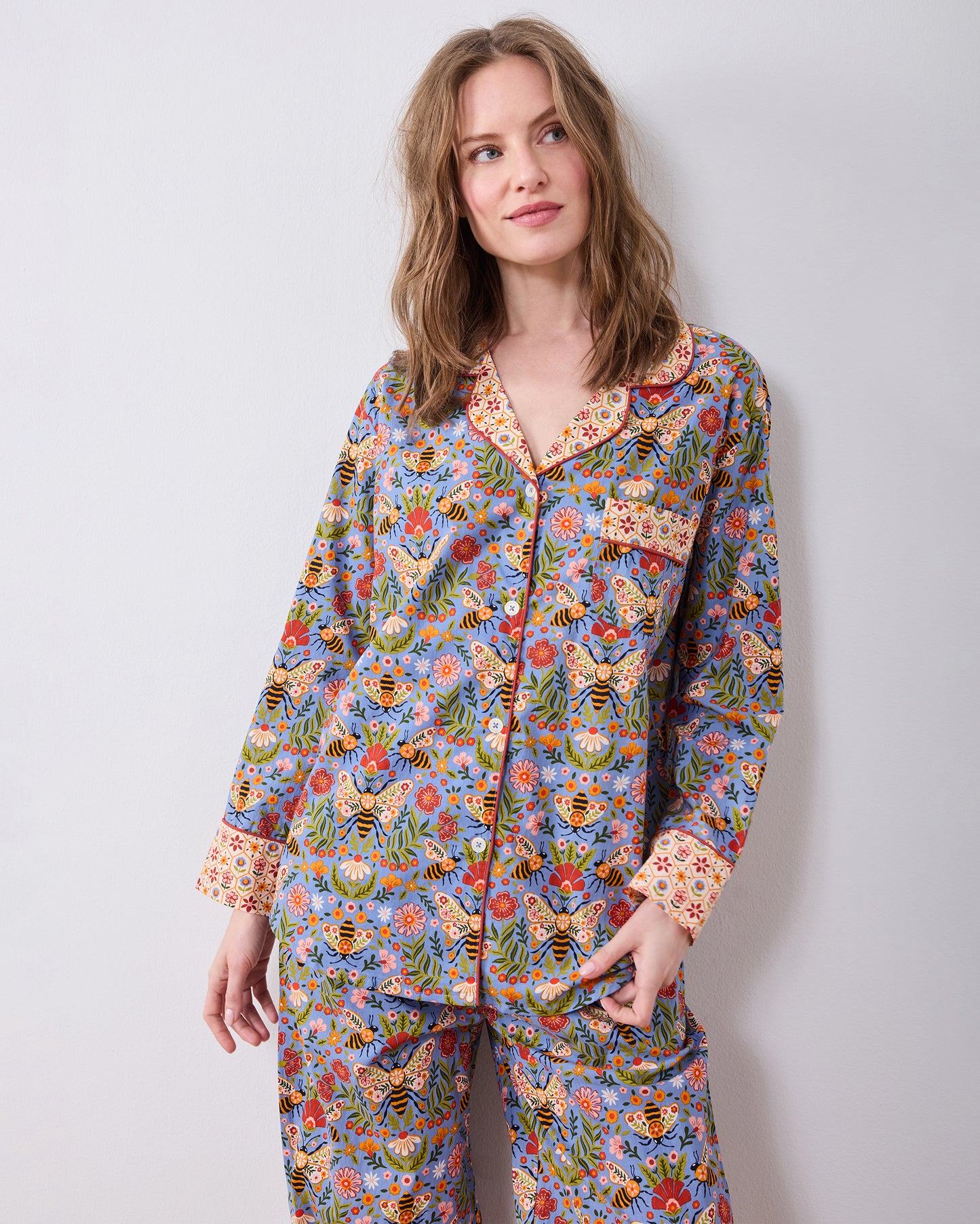 Front three-quarter view of the Bee Tapestry Delphinium Blue petite long pajama set, showing the button-down top, chest pocket, and matching printed pants.