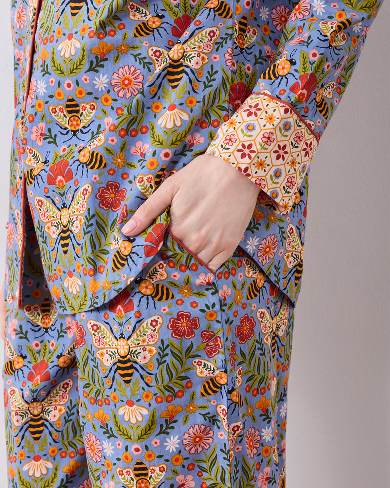Close-up detail of the Bee Tapestry Delphinium Blue pajama set, showing the floral and bee print, cuff, and hand in the pants pocket.