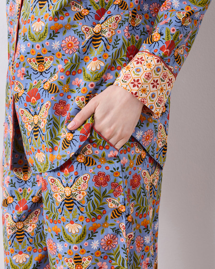 Close-up detail of the Bee Tapestry Delphinium Blue pajama set, showing the floral and bee print, cuff, and hand in the pants pocket.
