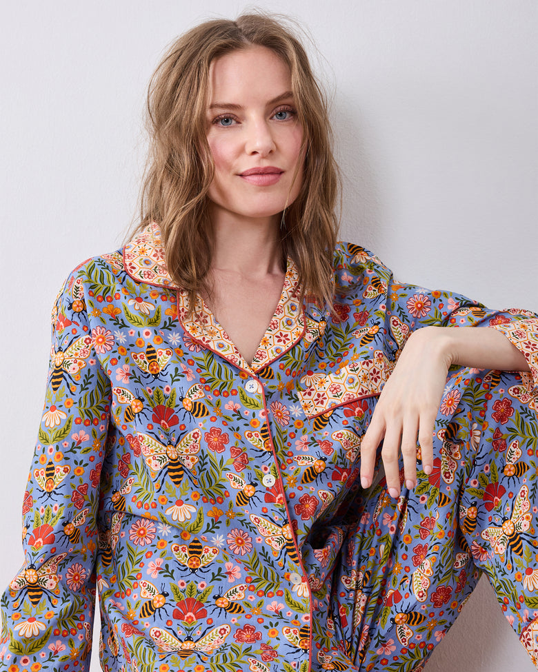 Seated front view of the Bee Tapestry Delphinium Blue petite long pajama set, showing the printed button-down top and matching pants.