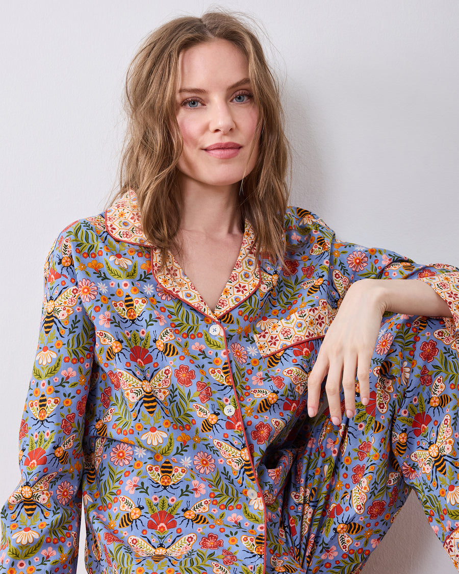 Seated front view of the Bee Tapestry Delphinium Blue petite long pajama set, showing the printed button-down top and matching pants.