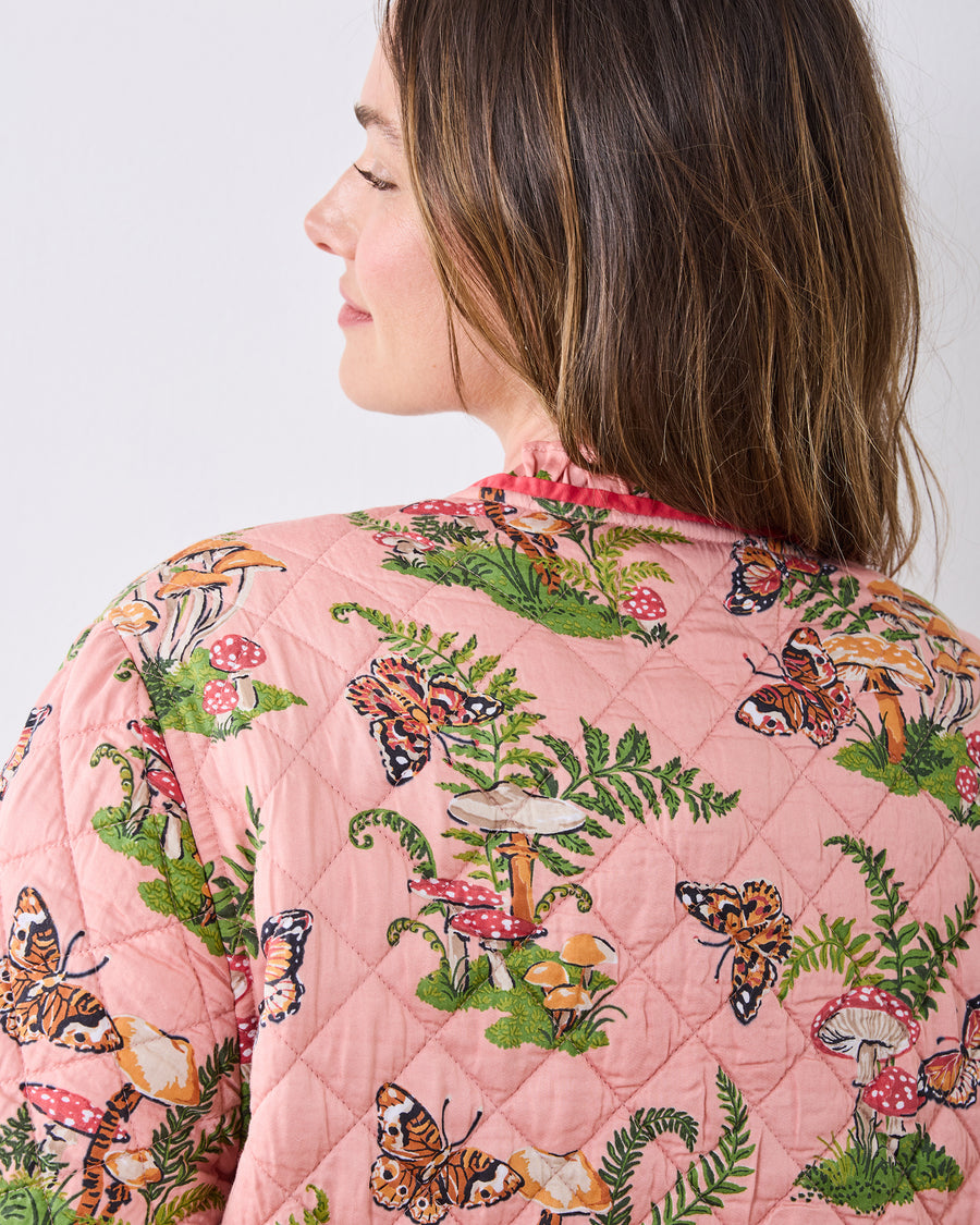 Back view of the quilted pink Butterfly Forager slumber jacket, showing butterflies, mushrooms, ferns, and the raised diamond stitching.