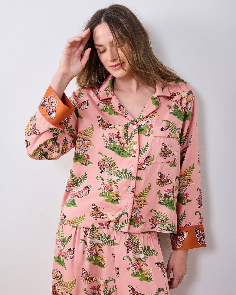 Front view of the pink Butterfly Forager petite satin Soho pajama set with a button-front top, long sleeves, wide-leg pants, and orange cuffs.