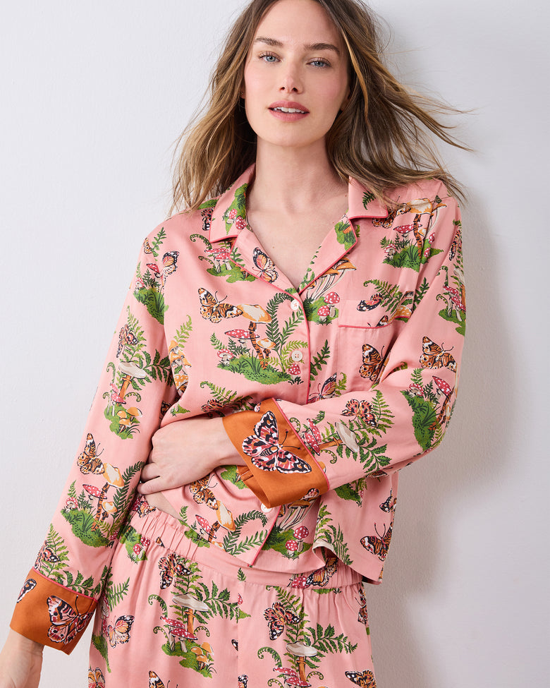 Model wearing the pink Butterfly Forager pajama set, showing the button-front top, chest pocket, wide-leg pants, and contrasting cuffs.