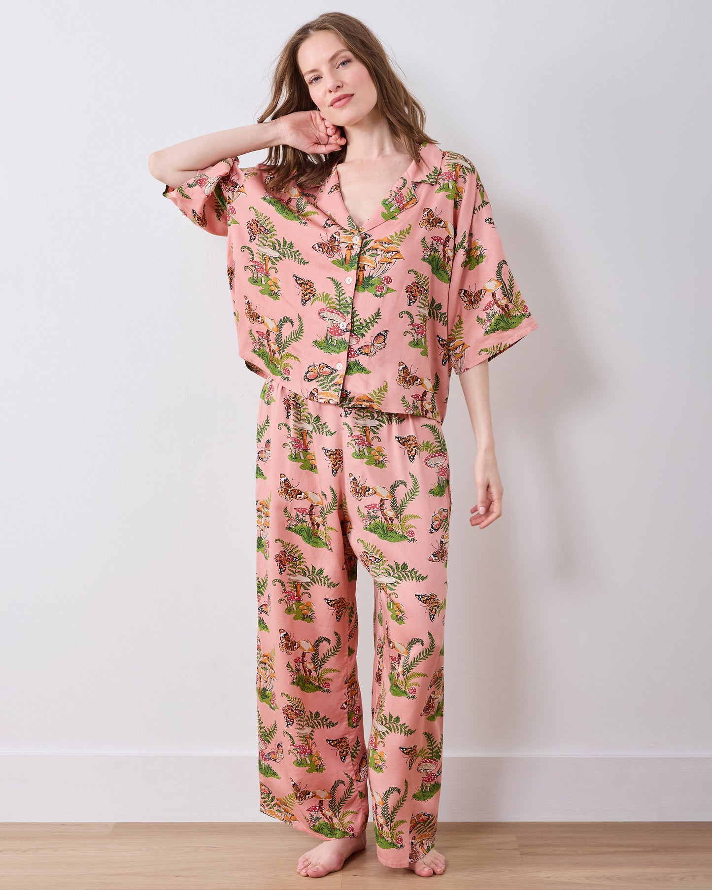 Full-length view of a person wearing a rosewood pajama set with a butterfly, mushroom, and fern print.