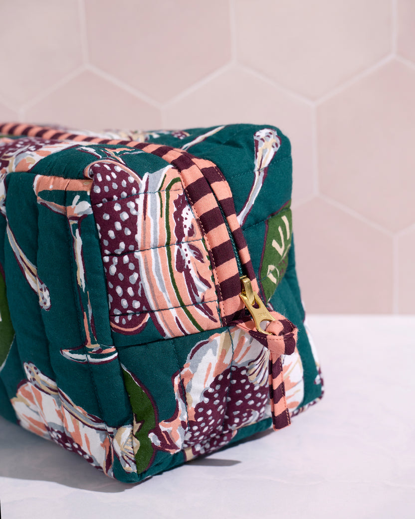 Close-up side view of the quilted Champagne & Caviar pouch showing its striped zipper edge and gold zipper pull.
