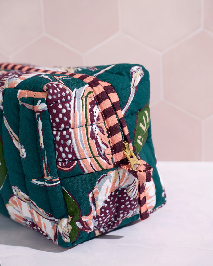 Close-up side view of the quilted Champagne & Caviar pouch showing its striped zipper edge and gold zipper pull.