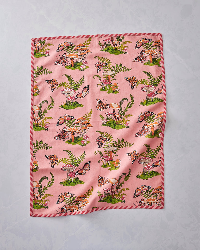 Front view of two pink Butterfly Forager tea towels laid flat, bordered with red-and-white stripes and printed with butterflies, mushrooms, and ferns.