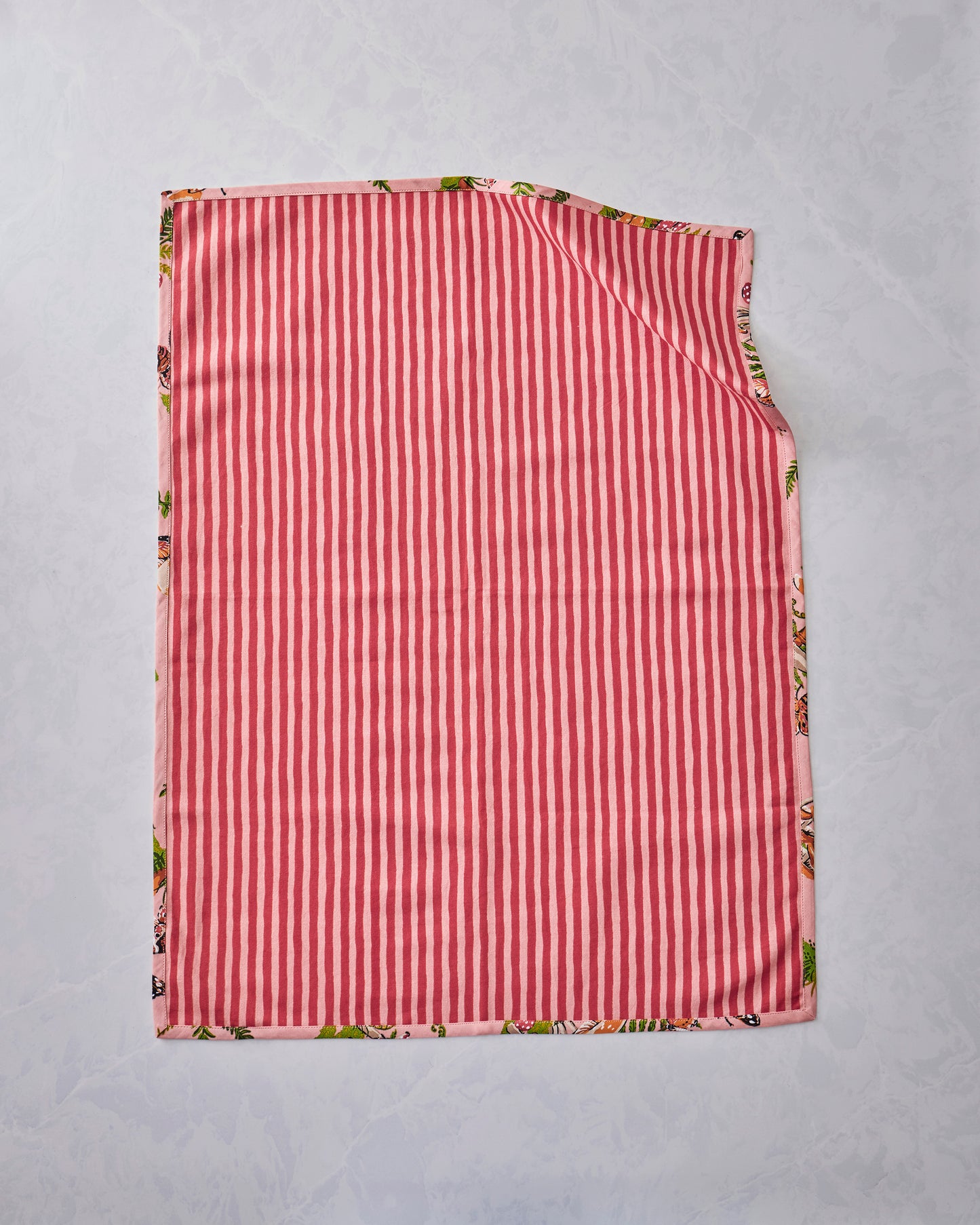 Back view of a Butterfly Forager tea towel showing a pink-and-red vertical stripe design, with the printed pattern visible along the edges.