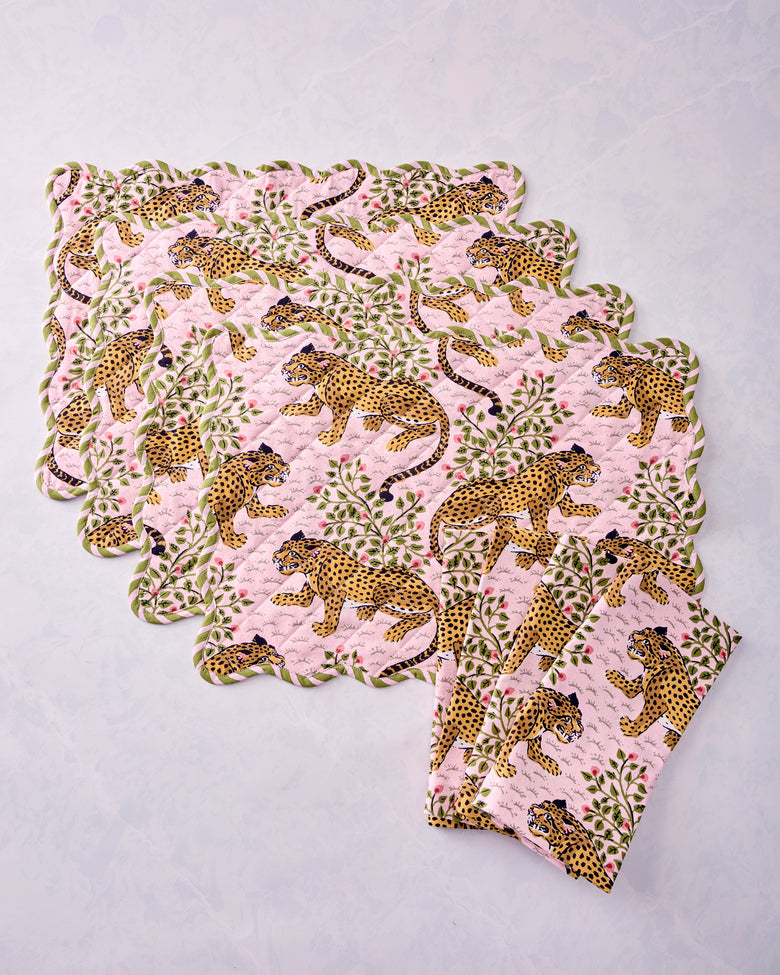 Four scalloped placemats and four folded napkins arranged to show the leopard and floral print