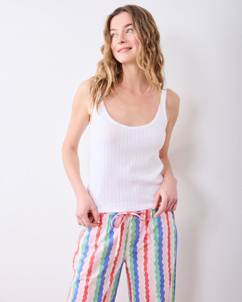 Model wearing a white tank and wavy multicolor pajama pants with a drawstring waist