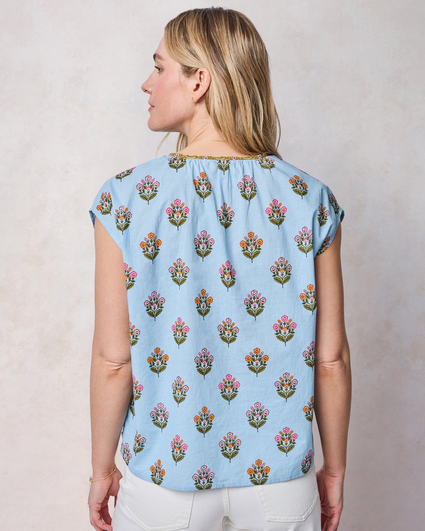 Back view of soft blue Jordan blouse with cap sleeves and a repeating floral motif