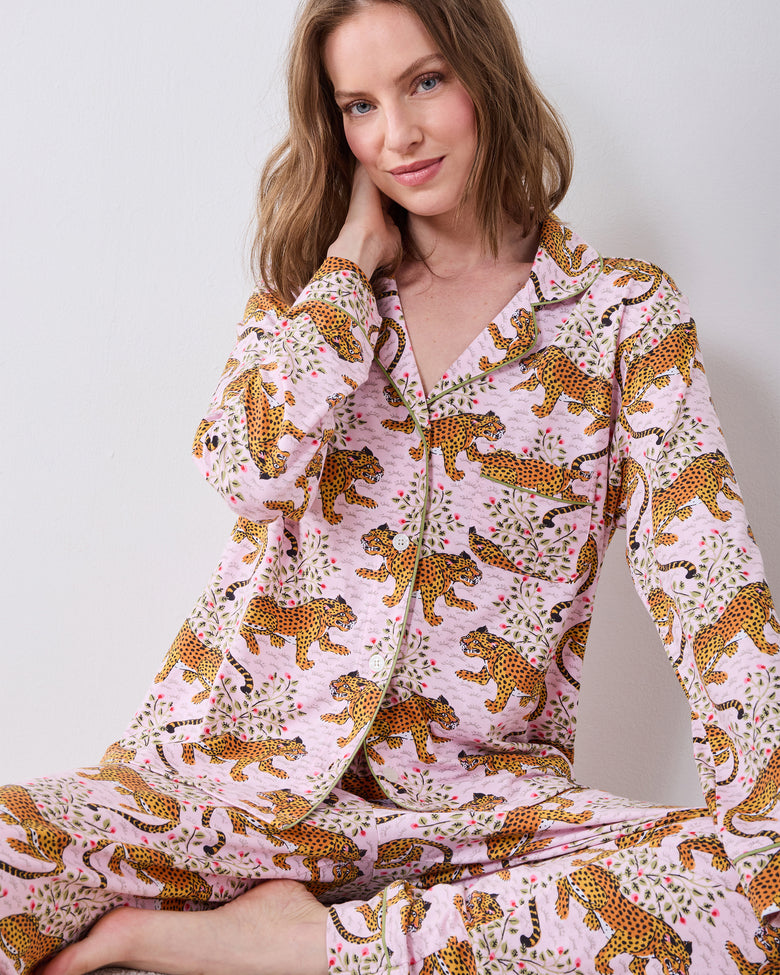 Seated front view of the Bagheera blush long pajama set with a button-down top, pants, and leopard print.