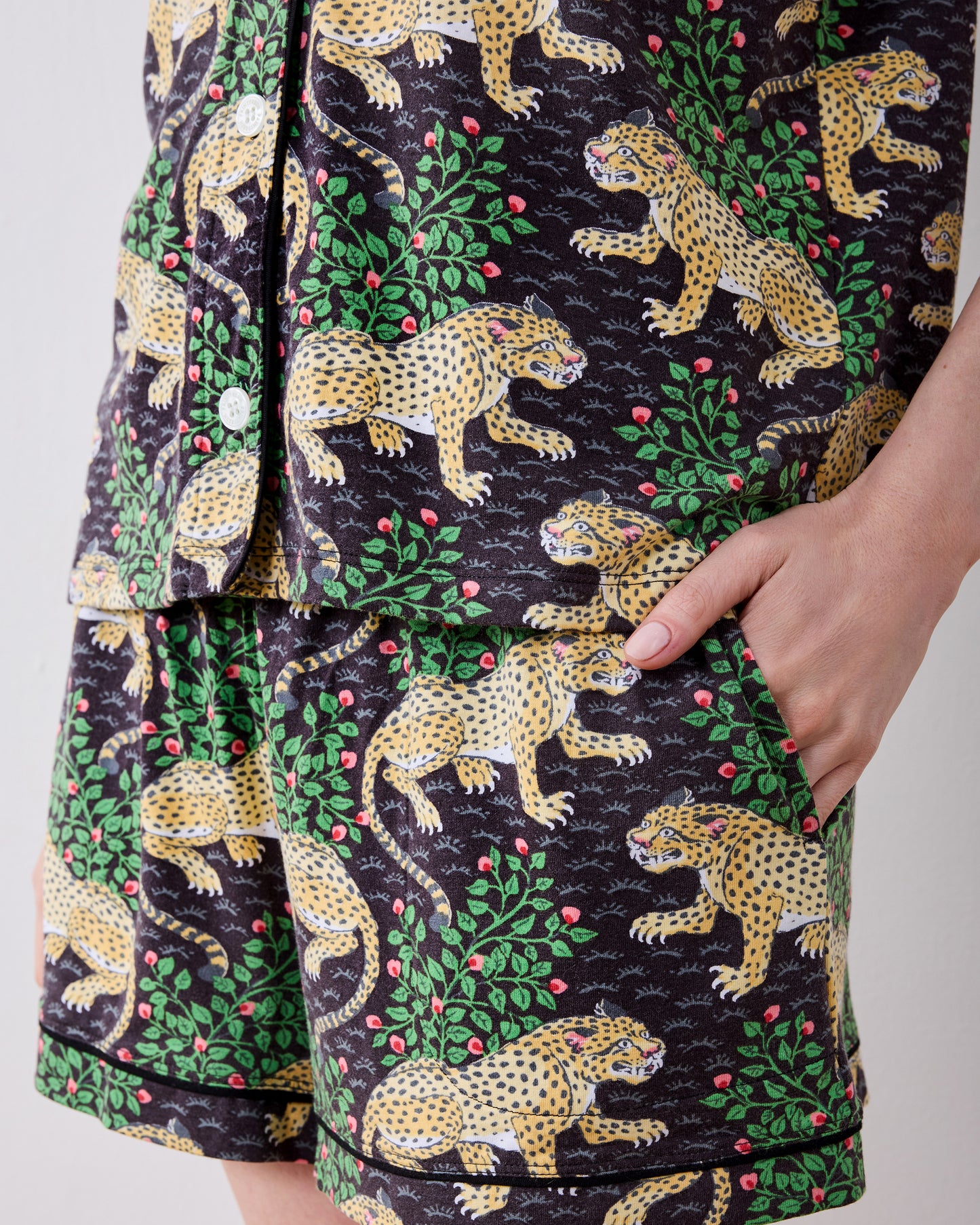 Close-up of the Bagheera short pajama set showing leopard-print shorts, a shirt hem, white buttons, and a side pocket.