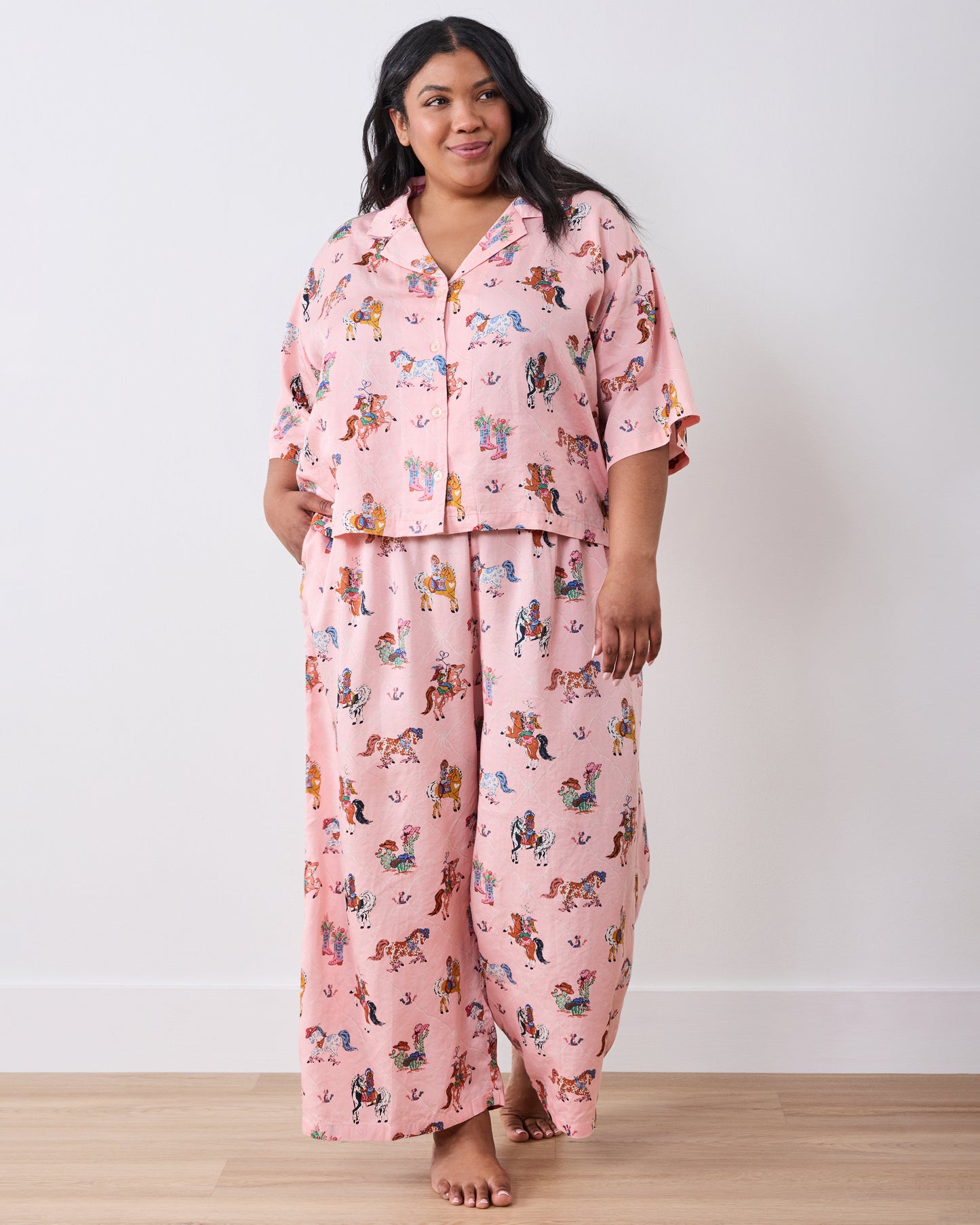 Full-length view of a model wearing the pink cowgirl-print petite pajama set with a short-sleeved top and wide-leg pants.
