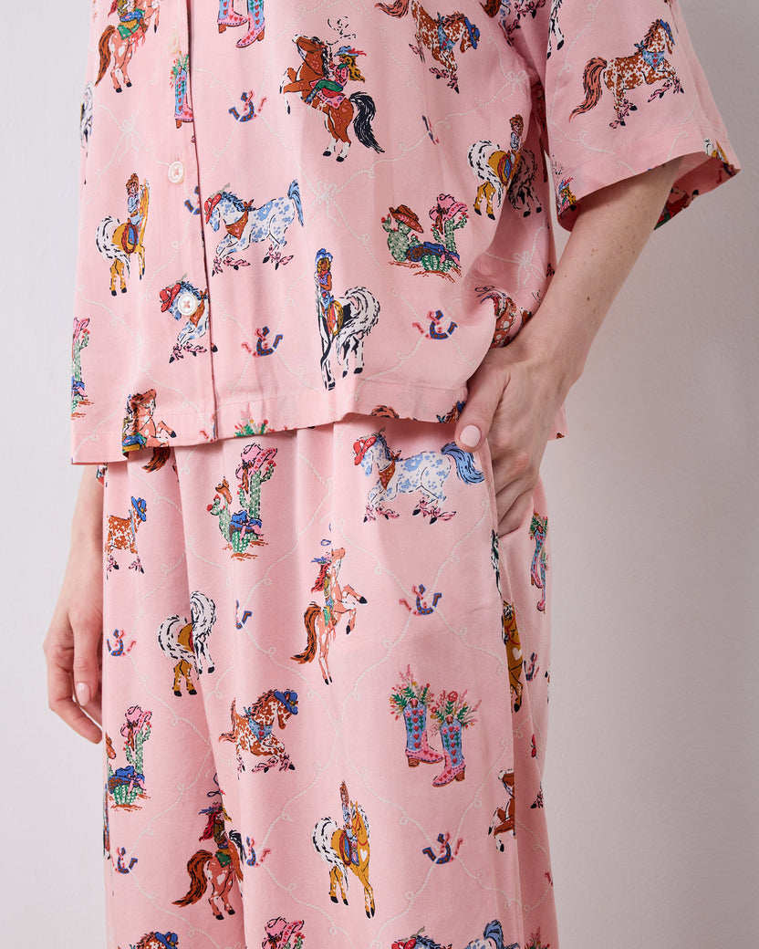 Close-up of the pink cowgirl-print pajama top and matching pants, showing the button placket and side pocket.
