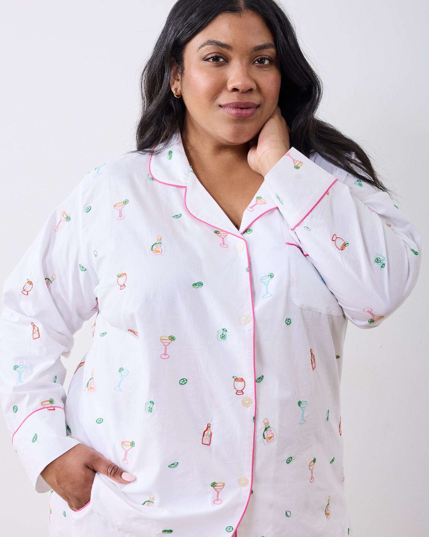 Close-up of a person wearing the long-sleeve cloud pajama top with pink piping and embroidered cocktail-themed motifs.
