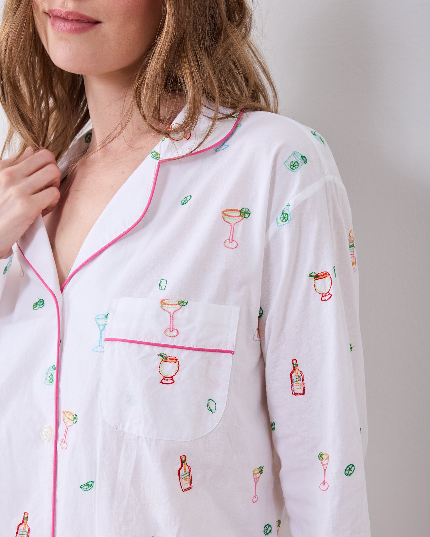 Close-up of the long pajama set's button-front shirt, contrasting piping, chest pocket, and cocktail-themed embroidery.