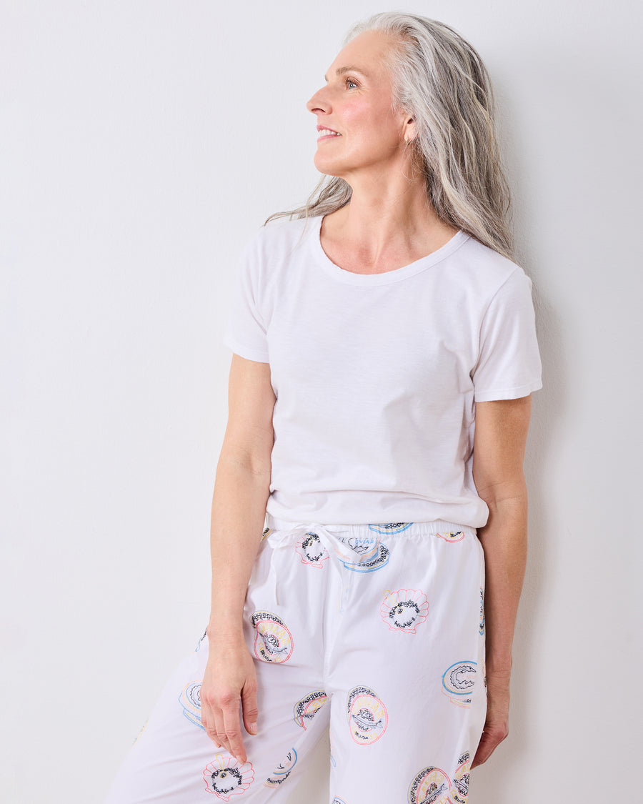 Upper-body view of a person wearing the pearl embroidered pajama pants with a plain white T-shirt.