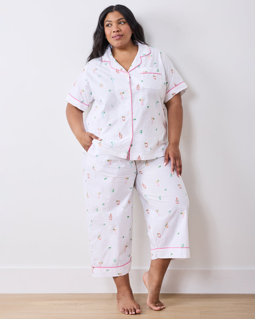 Front view of a person wearing the cloud short-sleeve pajama top and cropped pants with pink piping and embroidered cocktail-themed motifs.
