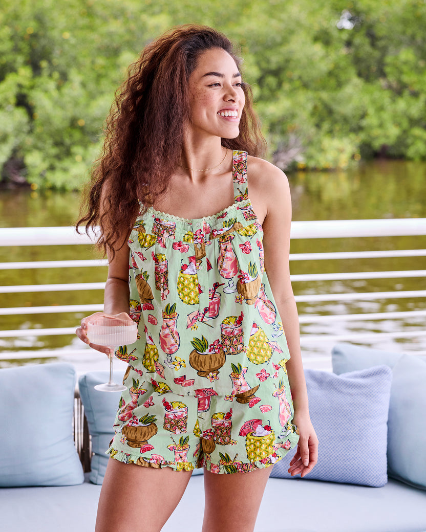 Mojito sleeveless top and ruffled shorts set shown by the water, with the model holding a drink
