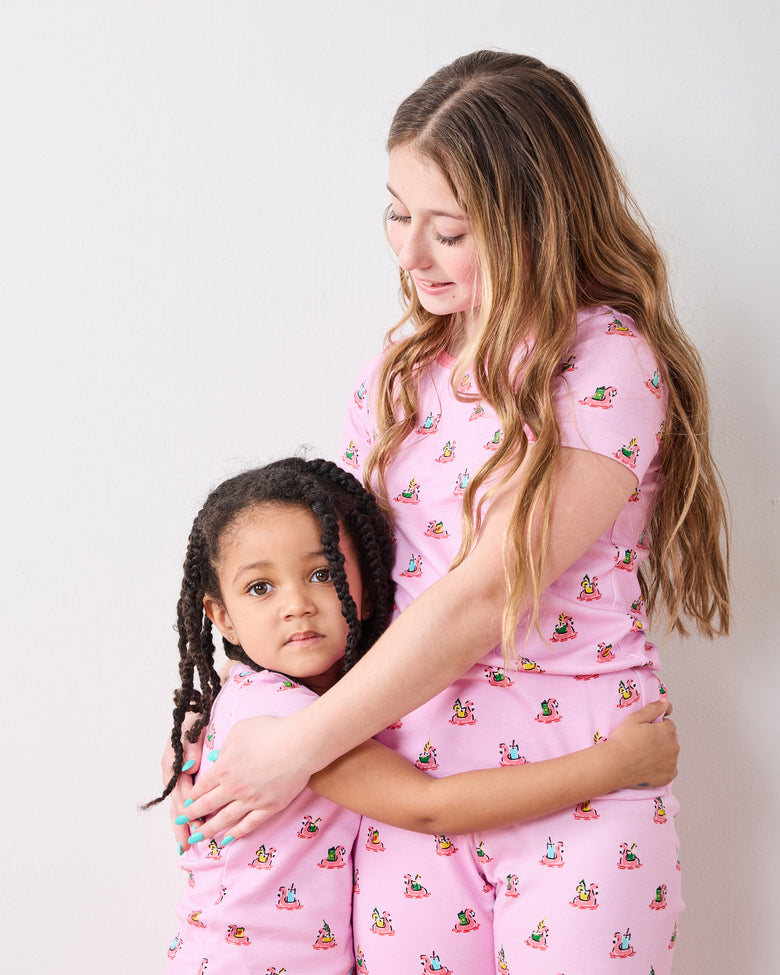 Two children embracing in matching pink Flamingo Floaties short-sleeve pajama sets