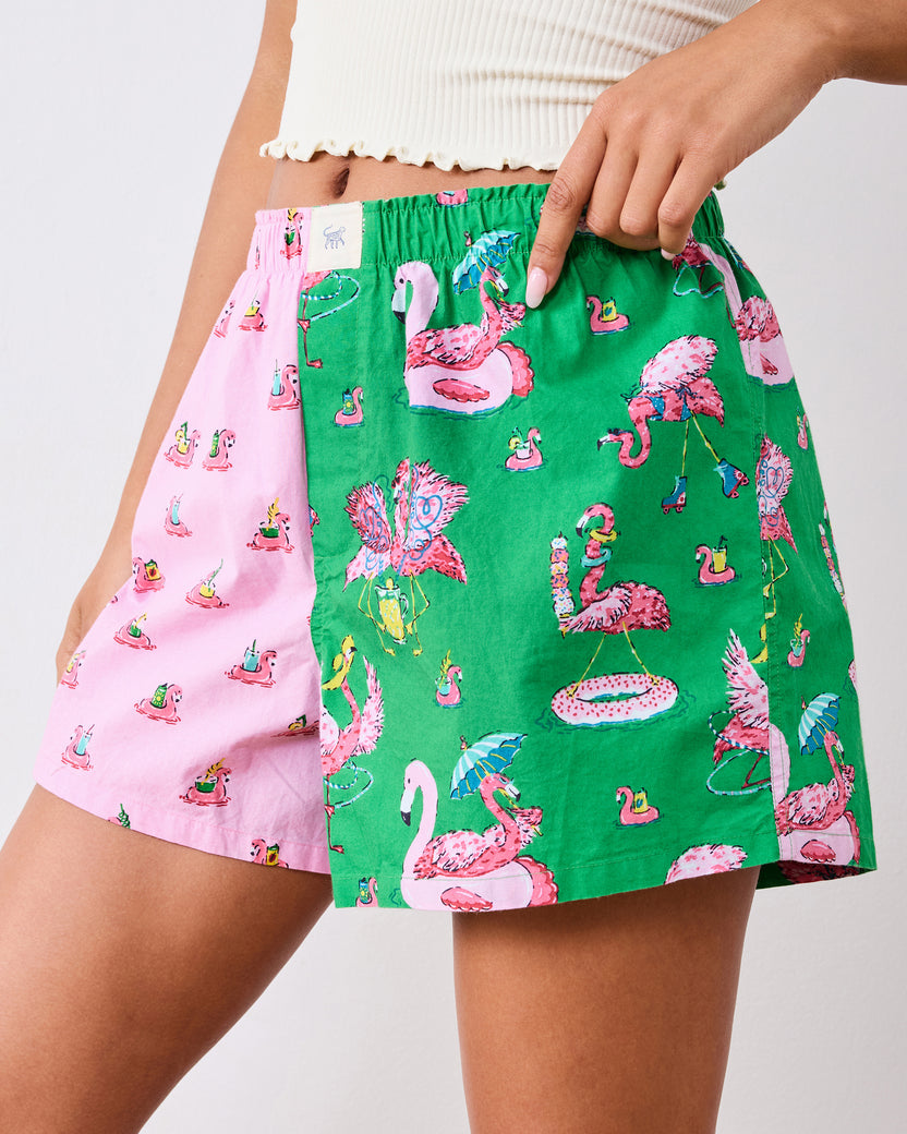 Close front view of the boxer shorts' elastic waistband, pink-and-green panels, and flamingo print